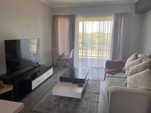 sala de estar con sofá y TV en Kay’s place, en Pretoria