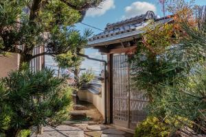 un cancello in un giardino con alberi e cespugli di Tamashima Tea Room – MAX 8ppl, PA / BBQ available 