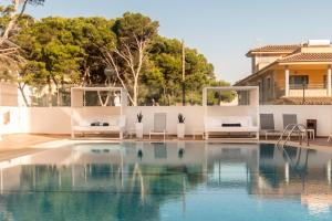 una piscina con sillas blancas y una piscina en Hotel Principe Wellness&Spa, en Playa de Palma