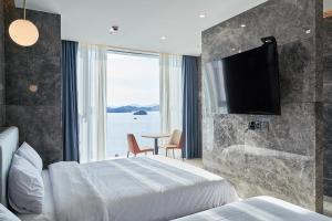 a hotel room with a bed and a flat screen tv at Yeosu Calacatta Hotel & Resort in Yeosu