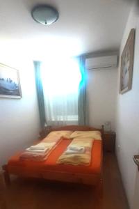 a bedroom with an orange bed with a window at Pedestrian Street Apartment in Hévíz