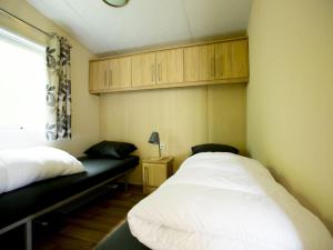 1 dormitorio con 2 camas, ventana y armarios en Recreatiepark Duinhoeve 13 en Udenhout