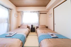 dwa łóżka w pokoju z oknem w obiekcie nestay apartment tokyo akihabara w Tokio