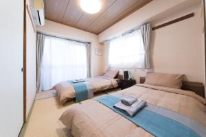 dwa łóżka w pokoju z dwoma oknami w obiekcie nestay apartment tokyo akihabara w Tokio