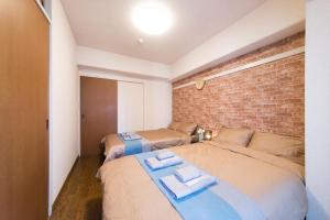 sypialnia z 2 łóżkami i ceglaną ścianą w obiekcie nestay apartment tokyo akihabara w Tokio