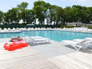 a swimming pool with white chairs and a red float at Holiday home Resort Mooi Bemelen II in Bemelen