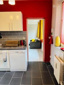 a kitchen with red walls and a white counter top at Bienvenue l'Opale Boulogne in Boulogne-sur-Mer