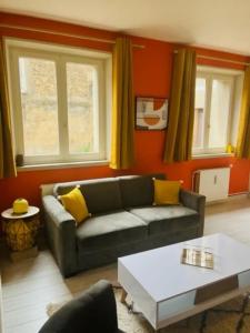 een woonkamer met een bank en twee ramen bij Bienvenue l'Opale Boulogne in Boulogne-sur-Mer