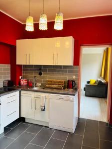 a kitchen with white cabinets and a red wall at Bienvenue l'Opale Boulogne in Boulogne-sur-Mer