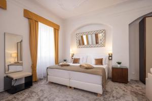 a bedroom with a white bed and a mirror at Bellevue Hotel Český Krumlov in Český Krumlov