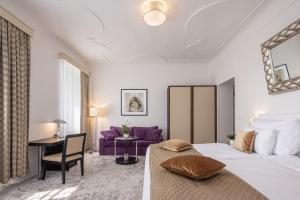 Bellevue Hotel Český Krumlov في تشيسكي كروملوف: غرفة نوم بسرير كبير وأريكة أرجوانية