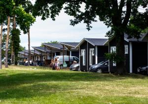a group of houses with cars parked in a yard at Kapelludden Camping & Stugor in Borgholm