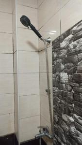 a shower head in a bathroom with a stone wall at NEWBORN CENTER hostel in Pristina