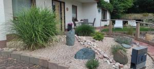 einen Garten mit Felsen und Pflanzen vor einem Haus in der Unterkunft Ferienwohnung Klein und Fein in Hemfurth-Edersee