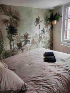 a bedroom with a bed with palm trees on the wall at Studio Jungle-Calme rue piétonne in Limoges