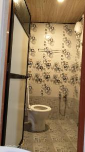 a bathroom with a toilet and a wall covered in musical notes at Mauli Cottage in Kashid