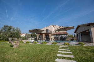 une maison avec deux parasols dans une cour dans l'établissement Villa Rosa by IstriaLux, à Loborika