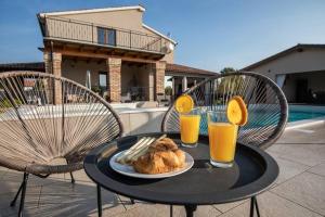 Villa Rosa by IstriaLux في Loborika: طاولة مع طبق من الطعام وكأسين من عصير البرتقال