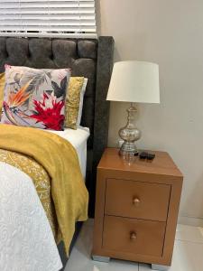 a nightstand with a lamp on it next to a bed at Le Rosette Residence in Empangeni