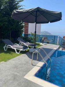 sombrilla y tumbonas junto a la piscina en Villa, Alanya, Antalya, en Alanya