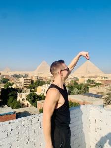 a man standing on a wall looking at the pyramids at LOAY PYRAMIDS VIEW in Cairo