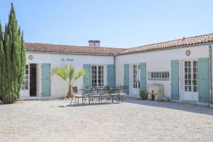 a house with tables and chairs in front of it at Le Clos du Pertuis in La Flotte