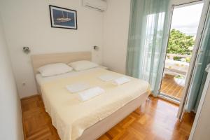 a bedroom with a bed with white sheets and a window at Apartmani Vidušin in Novalja