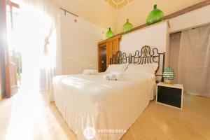 una camera da letto con un grande letto bianco con vasi verdi di Masseria Tenuta Le Menze a Cavallino di Lecce