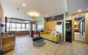 a living room with a yellow couch and a kitchen at Kkaebi Stay in Pohang