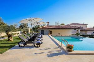 a row of lounge chairs next to a swimming pool at Villa Fierra by IstriaLux in Svetvinčenat