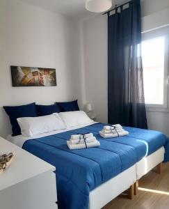 - une chambre avec un lit bleu et des serviettes dans l'établissement Appartamento a Pirri, via E. Toti. Cagliari. Rosas Rooms., à Cagliari