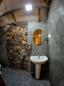 a bathroom with a stone wall and a sink at LAMIACEAE WOOD CABIN in Ella