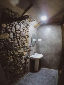 a bathroom with a sink and a stone wall at LAMIACEAE WOOD CABIN in Ella