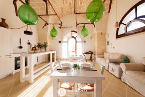 uma sala de estar com uma mesa e luzes pendentes verdes em Masseria Tenuta Le Menze em Cavallino di Lecce