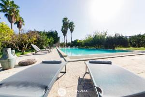 - une rangée de chaises longues à côté de la piscine dans l'établissement Masseria Tenuta Le Menze, à Cavallino di Lecce