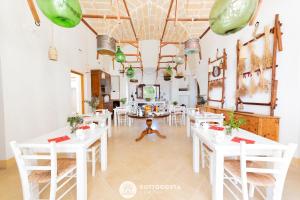 uma sala de jantar com mesas brancas e cadeiras brancas em Masseria Tenuta Le Menze em Cavallino di Lecce