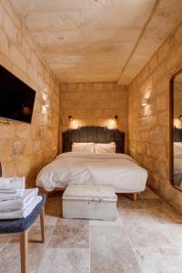 a bedroom with a bed in a stone wall at Talbot House by Talbot & Bons in Luqa