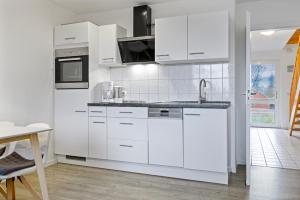 eine weiße Küche mit weißen Schränken und einem Waschbecken in der Unterkunft Urlauberdorf Urlauberdorf 33b in Boltenhagen