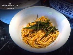 a white bowl of pasta with greens on top at Radisson Collection Hyland Shanghai in Shanghai