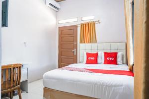 1 dormitorio con 1 cama con almohadas rojas en OYO 93470 Bans Kostel, en Lampung
