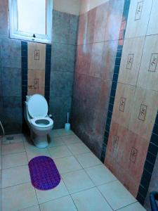 łazienka z toaletą i fioletowym dywanem w obiekcie Bamburi 2 bedroom Luxury homes w mieście Bamburi