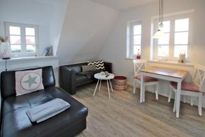 a living room with a black leather couch and a table at Doerpstraat 9_ Whg_ 8 in Wyk auf Föhr