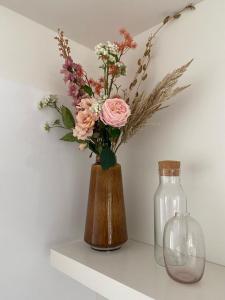 a vase with flowers in it sitting on a shelf at Recent en lichtrijk duplex-appartement te Wenduine in Wenduine