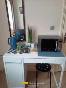 a white desk with a microwave and a counter top at Goldy's place in E17 in London