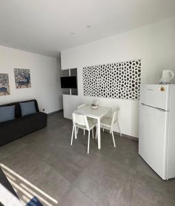 eine Küche mit einem weißen Tisch und einem weißen Kühlschrank in der Unterkunft Case Costy in Aci Castello