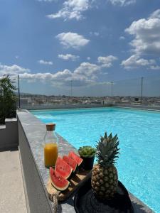 a tray of fruit and a drink next to a swimming pool at Luxury Maisonette with Shared Pool in Athens