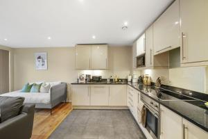 a kitchen with white cabinets and a couch in a room at LiveStay-Stunning 2 Bed 2 Bath Apartment in Maida Vale in London