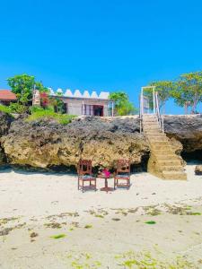 dos sillas sentadas en una playa con una casa en Makunduchi Waterfront paradise, en Tongoni