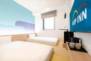 una camera d'albergo con due letti e una televisione di Hop Inn Tokyo Asakusa a Tokyo