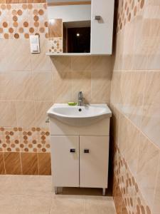 W łazience znajduje się biała umywalka i lustro. w obiekcie Krisz Apartman w mieście Gyula